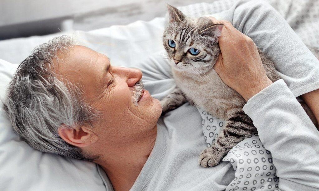 A man cuddling with a cat in bed.